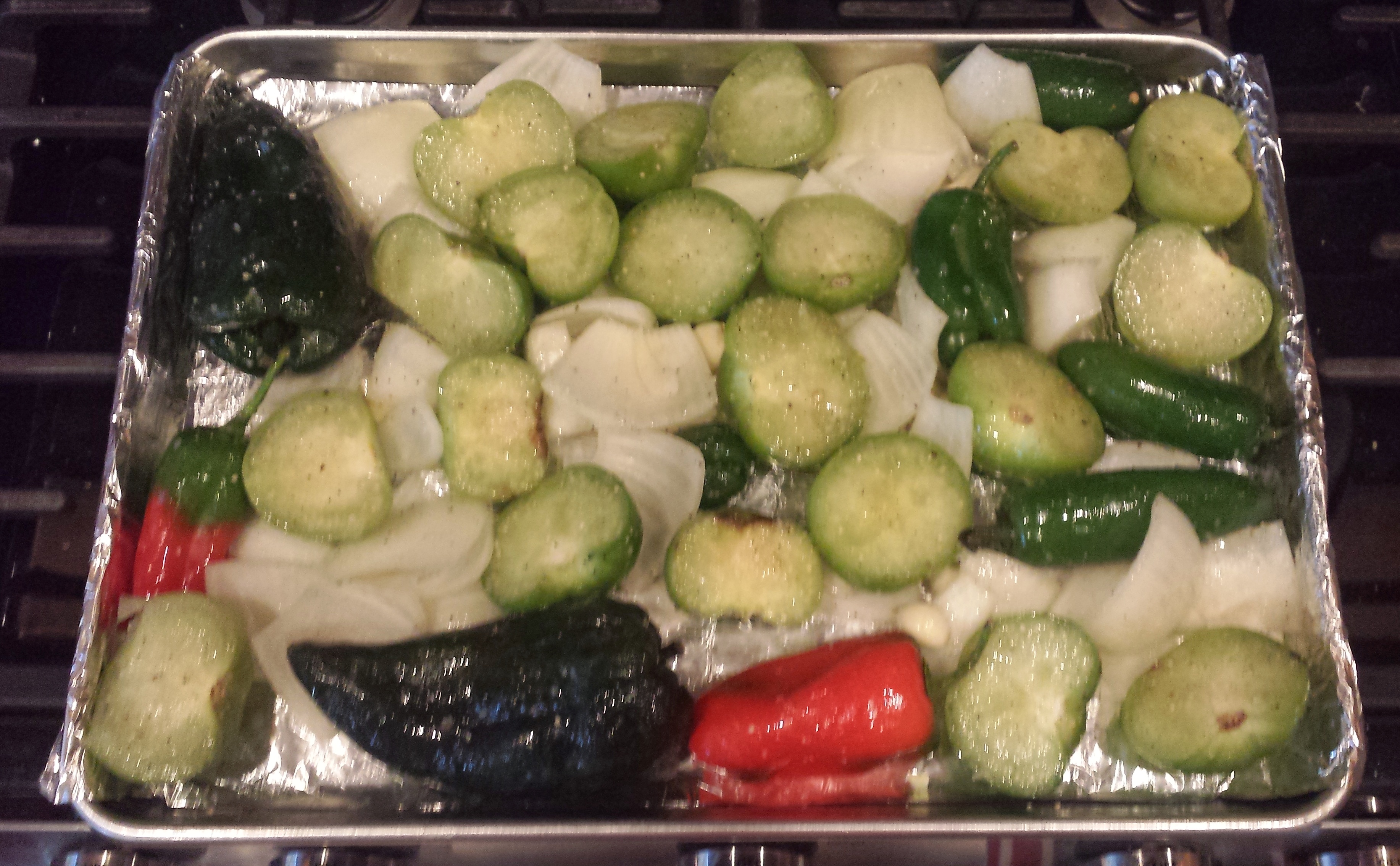 Tomatillos, jalapenos, poblanos, bell peppers, onions and garlic before being roasted.